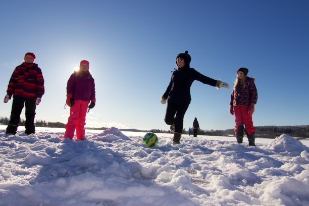 Oppilaat pelaamassa jalkapalloa ulkona talvella.